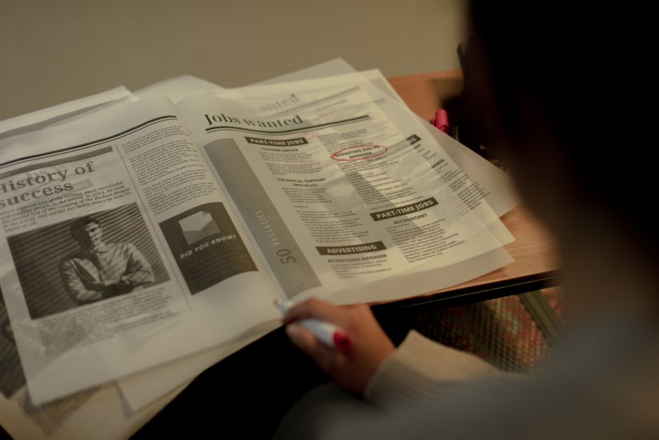 新聞の求人欄をピンクの蛍光ペンで印をつけながら読んでいる手元の写真