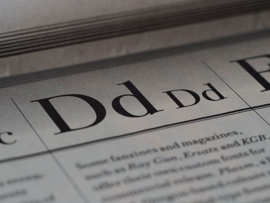 英字新聞の紙面が重なり、見出しと本文の文字が並んでいる様子のクローズアップ