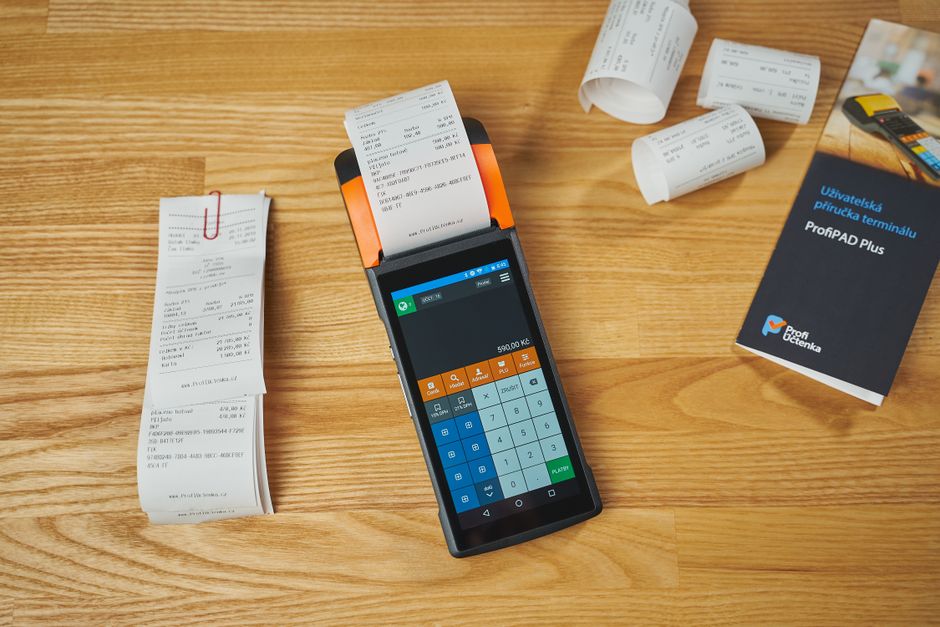 木製のデスクに置かれた電子決済端末と、そこから印字されたレシート